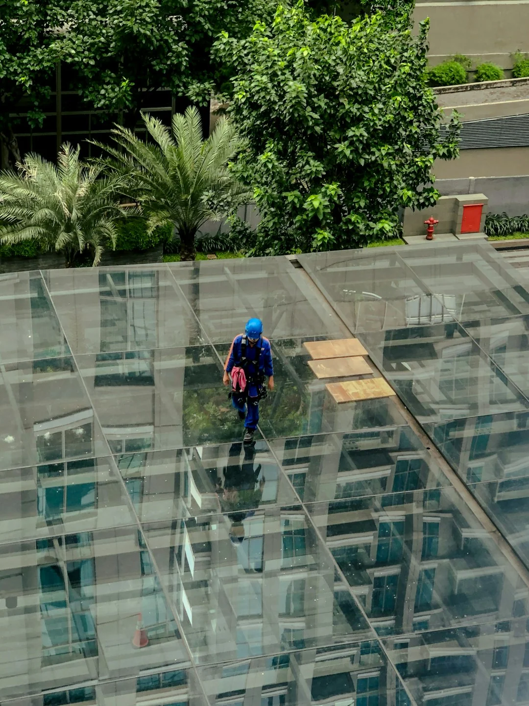 A person in protective gear sanitizing an office desk using fumigation equipment during daytime.